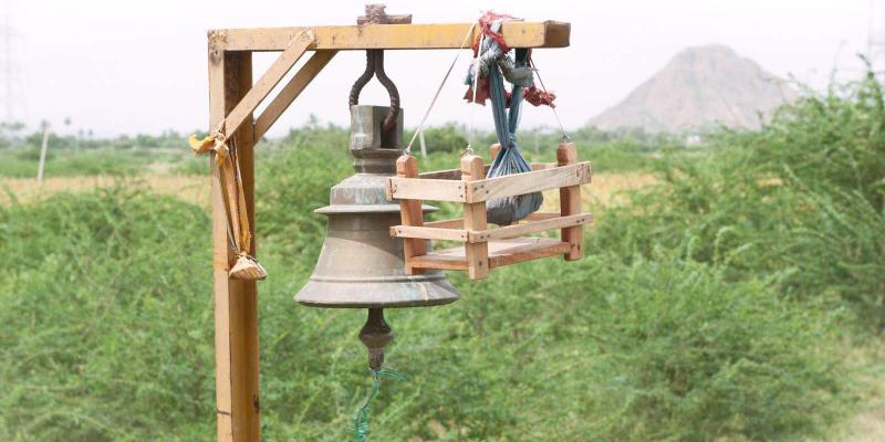 A temple bell with offerings tied to it.