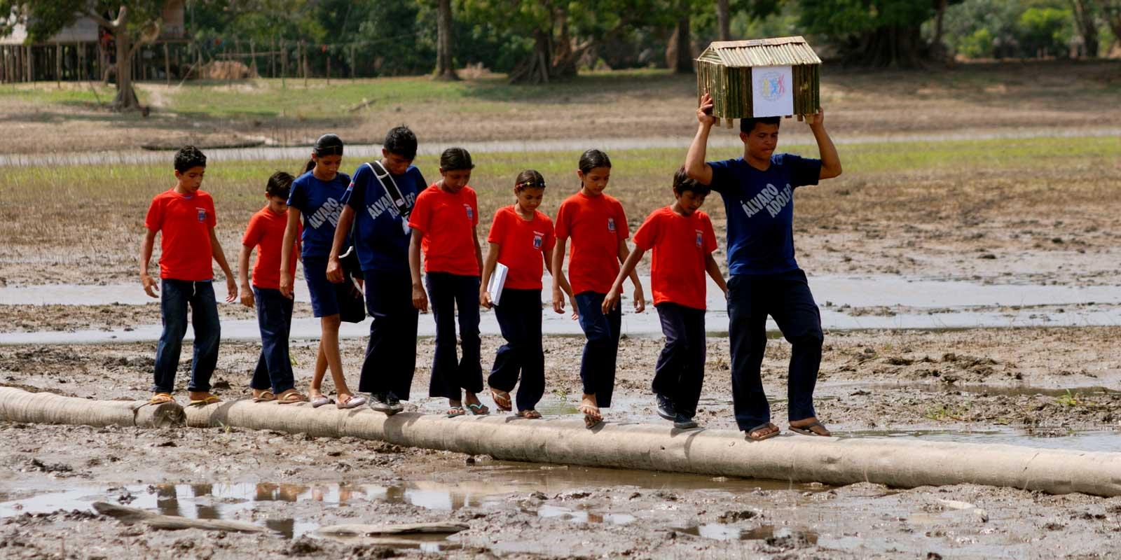 a group of people with a ballot box walking through mud.