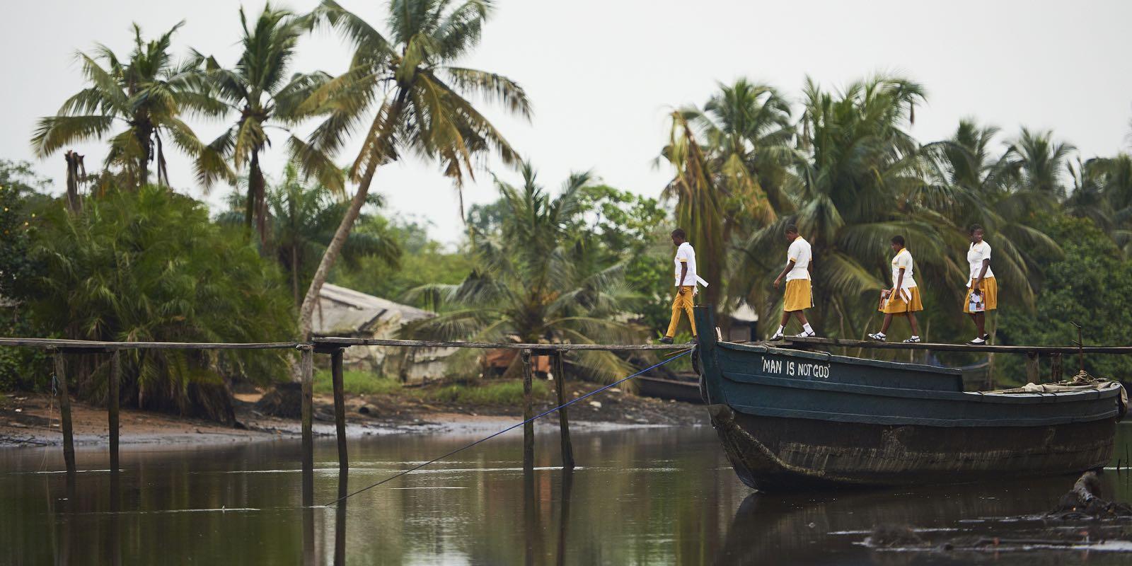 Four young Child Rights Ambassadors walk on a bridge across the water.