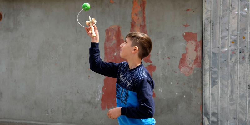 Dario playing outside with Kendama toy