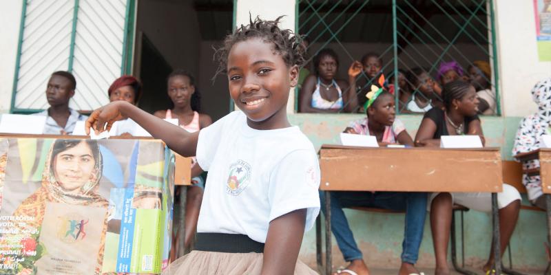 Girl casting vote in ballot box.