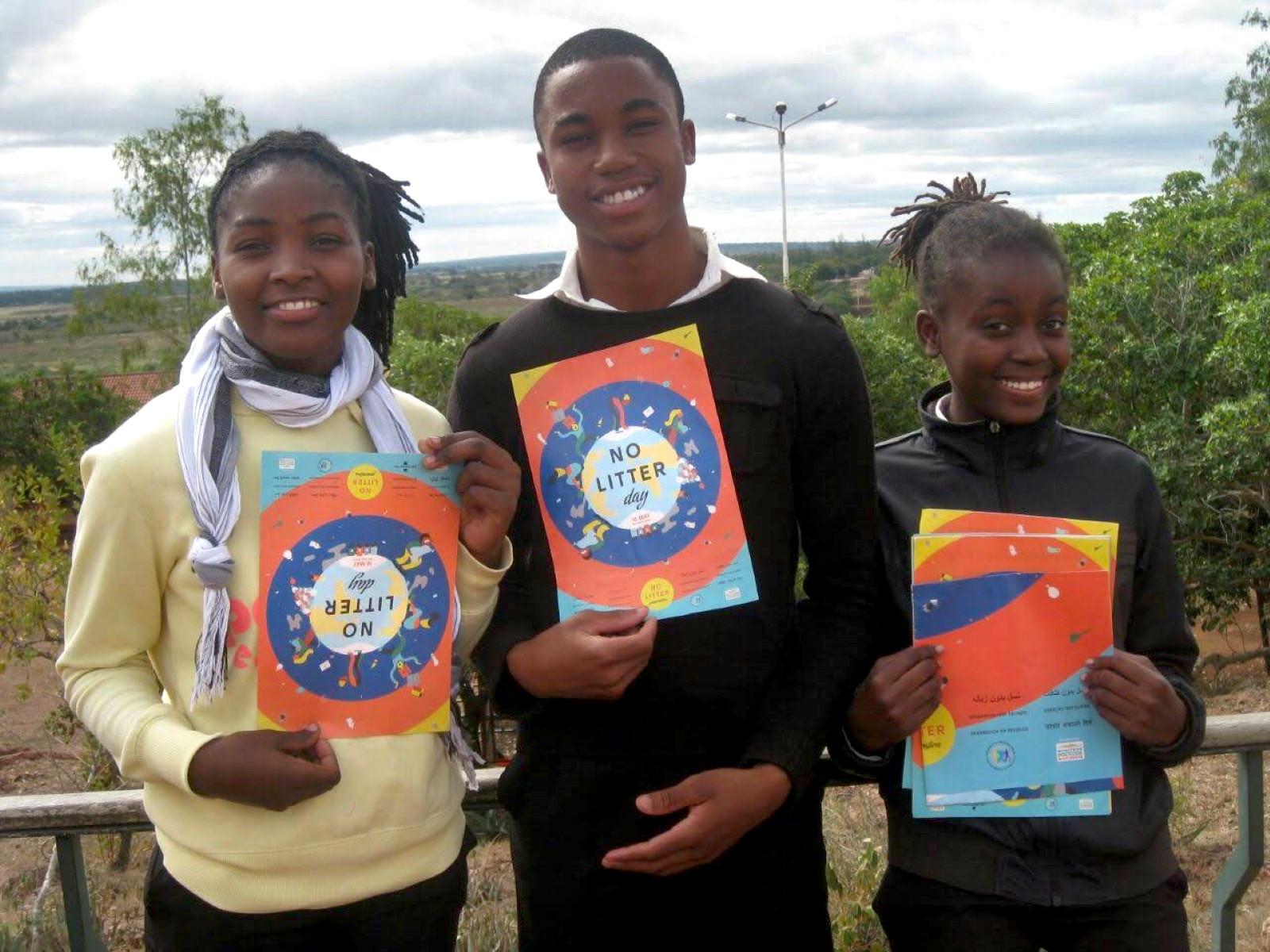 Three older children holding posters