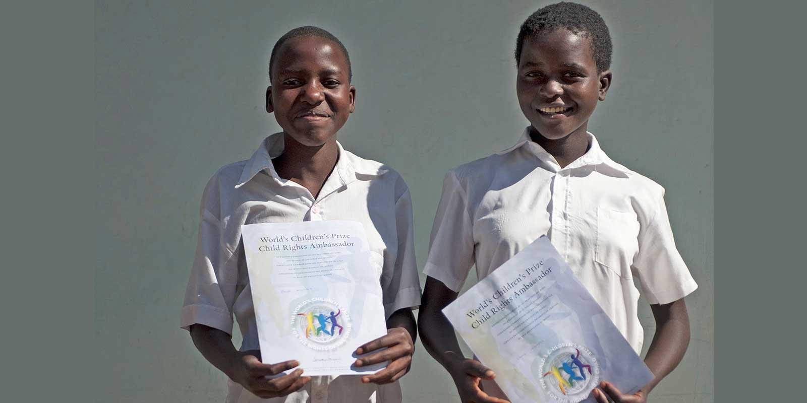 Pride and Loveness standing with diplomas