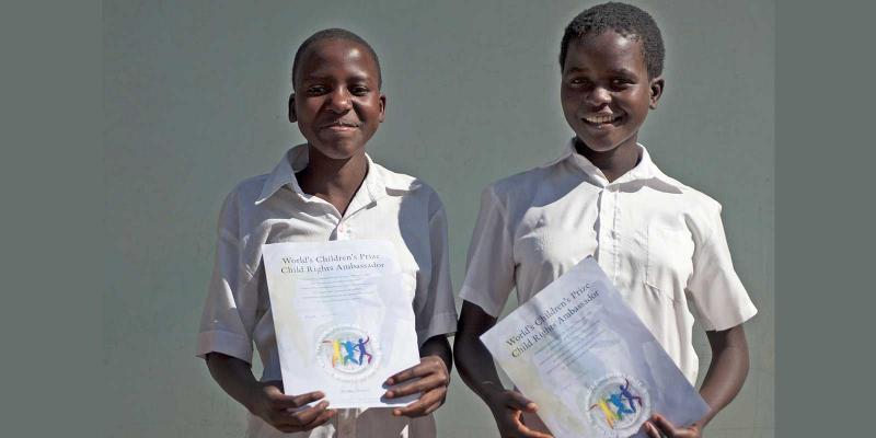 Pride and Loveness standing with diplomas